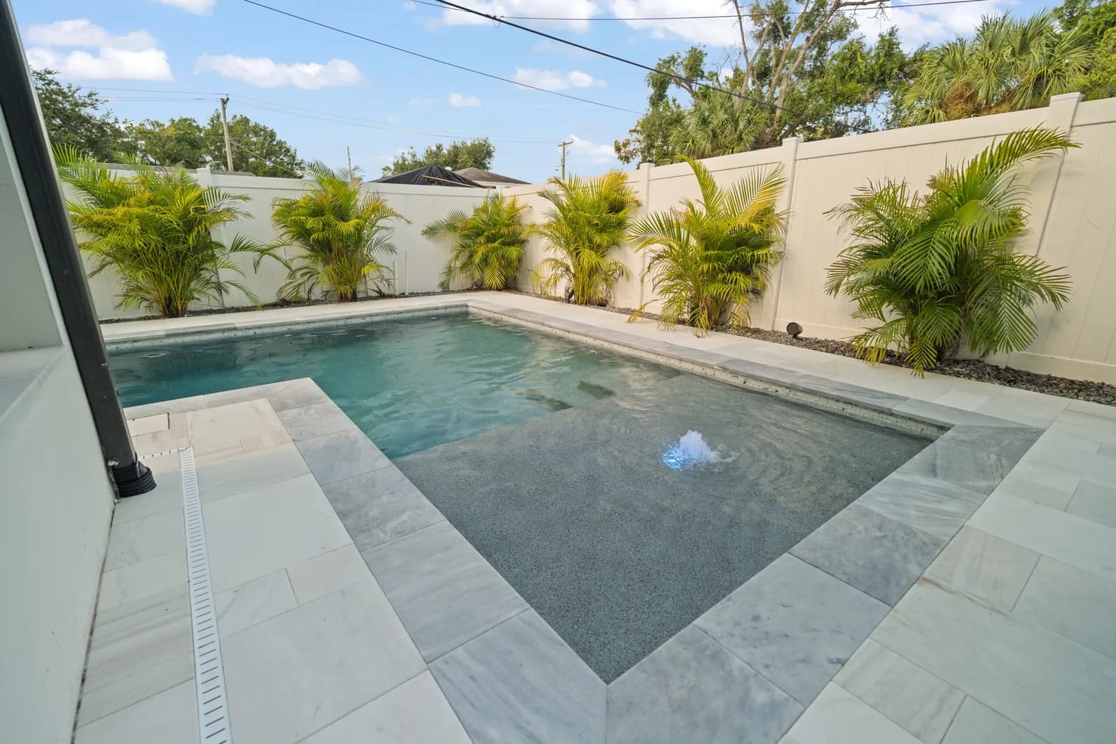 Custom Tampa Bay pool with a tanning shelf and bubbler, comfortable to swim year-round, built by LIV Pools