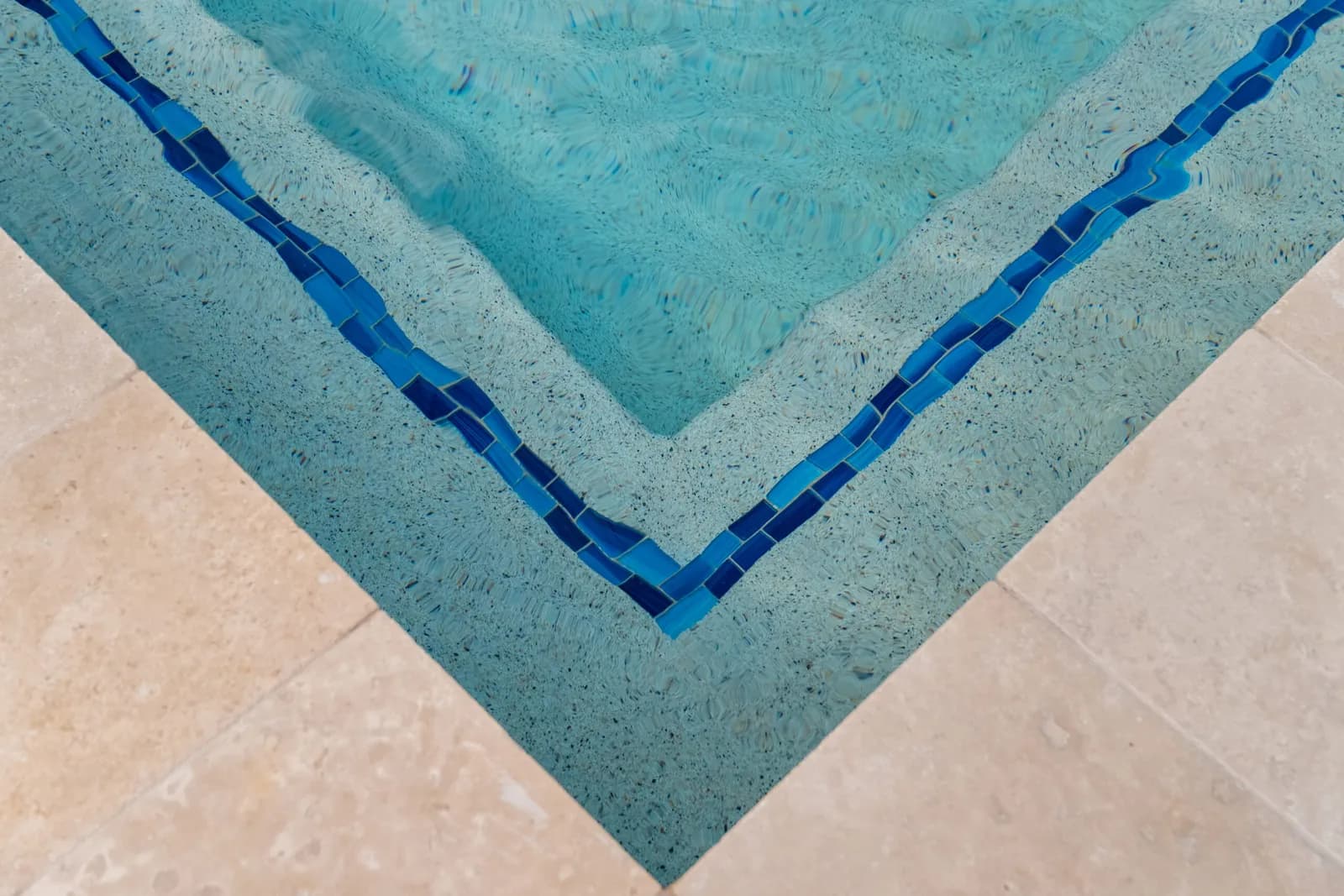 New waterline tile, pebble interior, and travertine coping on a resurfaced Tampa Bay pool by LIV Pools